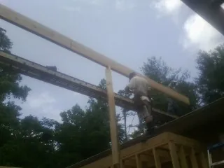 Carpenter setting a ridge beam over a new addition frame — Ice Dam Removal by Roofing Brothers in Alvaton