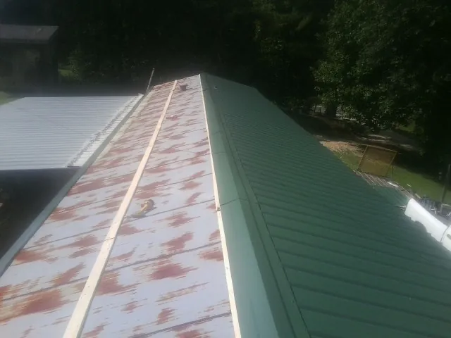 Old rusted panels beside newly installed green metal roofing — Wind Damage Roof Repair by Roofing Brothers in Alvaton