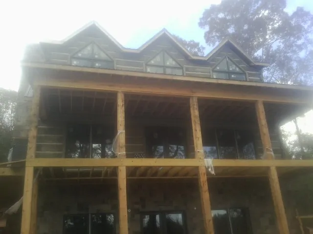 Dormers and porch framing on a large log home under construction — Roof Coating work by our crew in Alvaton