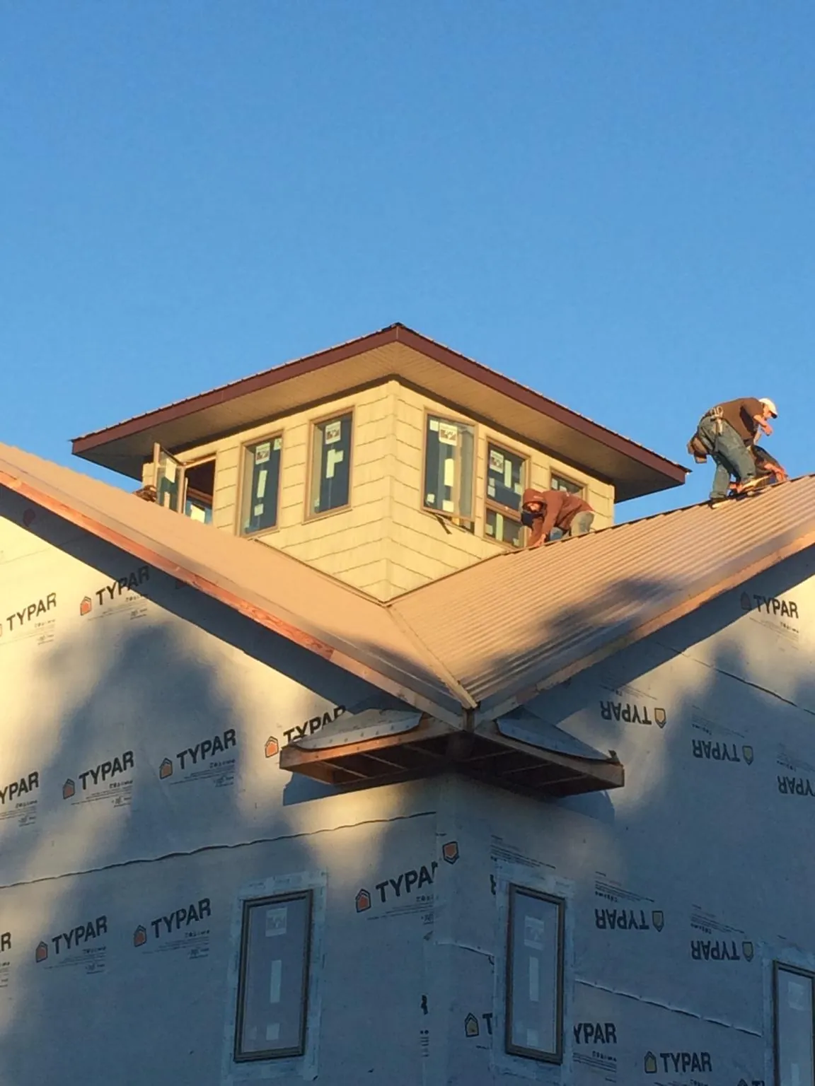 Roofers working around a rooftop cupola on a new metal roof at sunset — Roof Waterproofing in Alvaton by Roofing Brothers